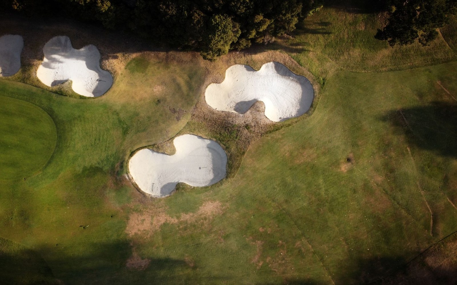 Aerial view of curved white sand bunkers on a green golf course fairway