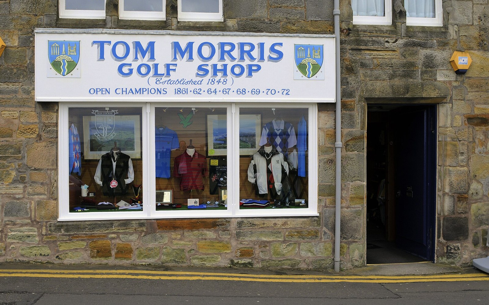 Stone storefront of Tom Morris Golf Shop with mannequins displaying golf apparel in the window