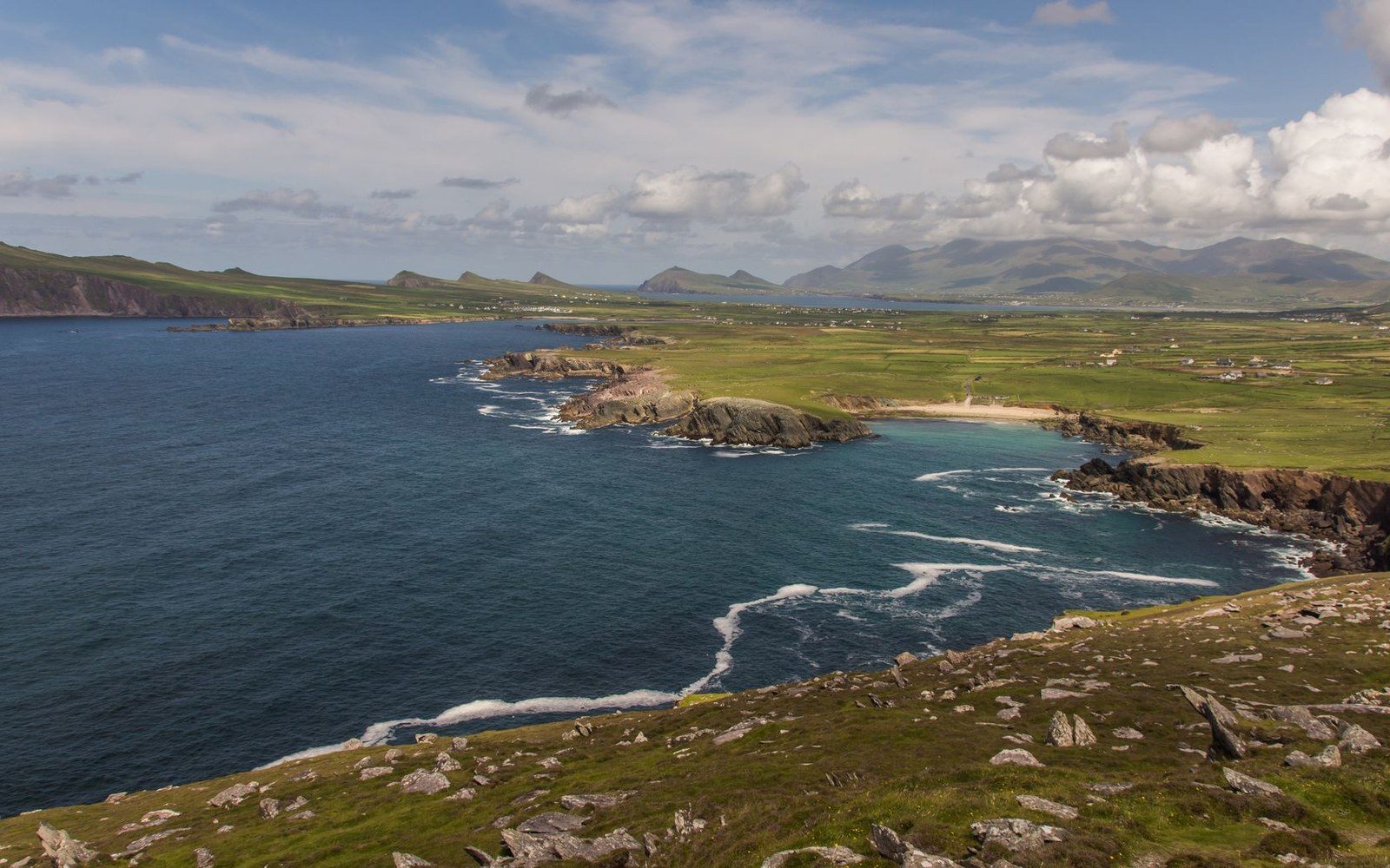 Rugged coastline with green headlands and waves breaking along rocky cliffs
